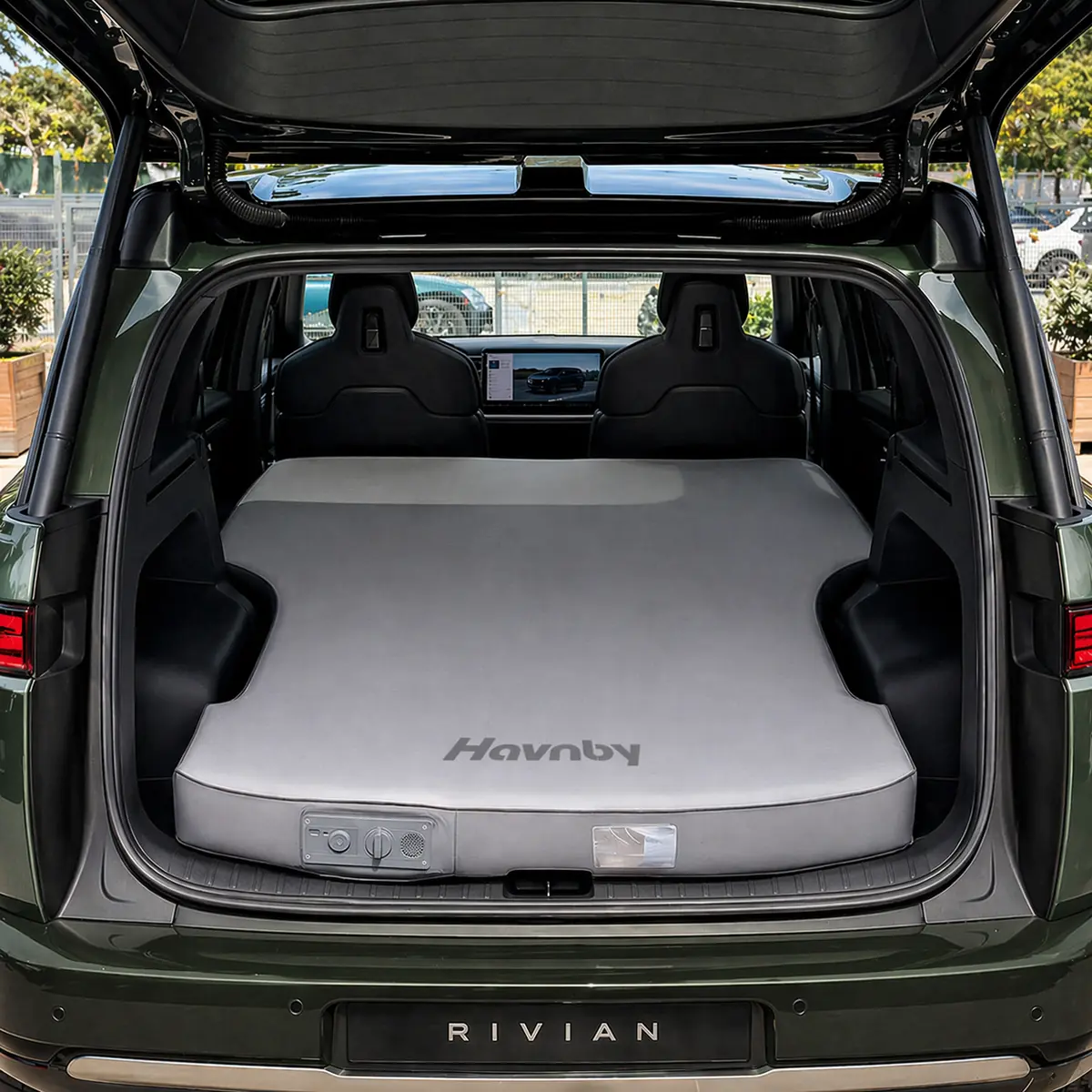 Havnby CloudCore mattress filling the rear cargo area of a Rivian-badged SUV, viewed through the open tailgate with the second-row seats folded