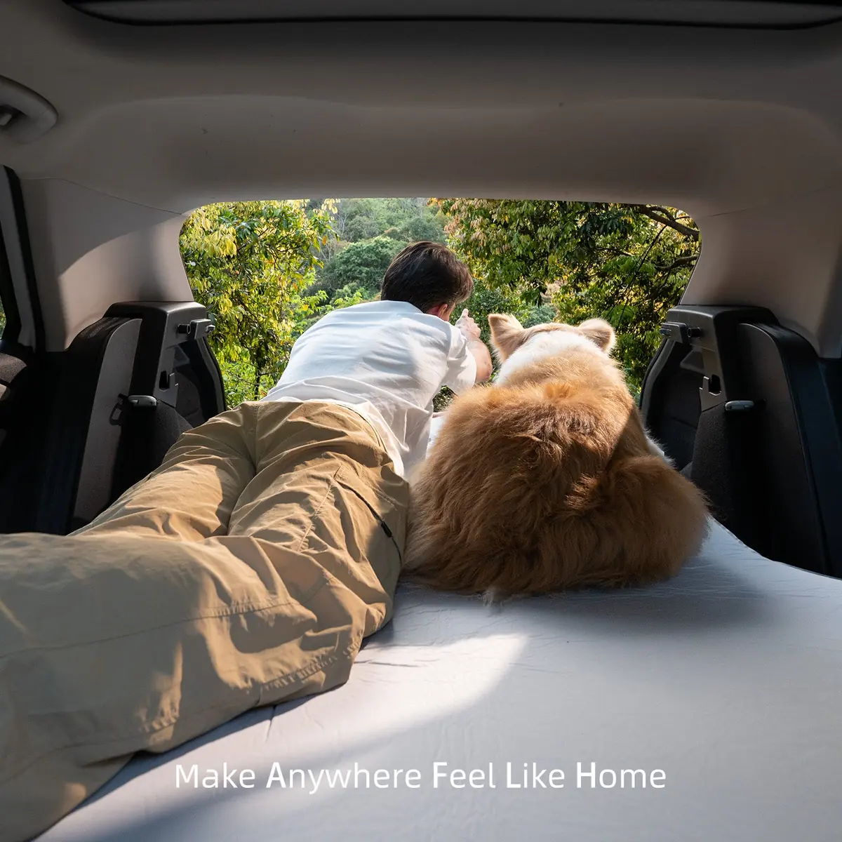 View from inside the vehicle cargo area looking out through the open tailgate at a man and dog outdoors