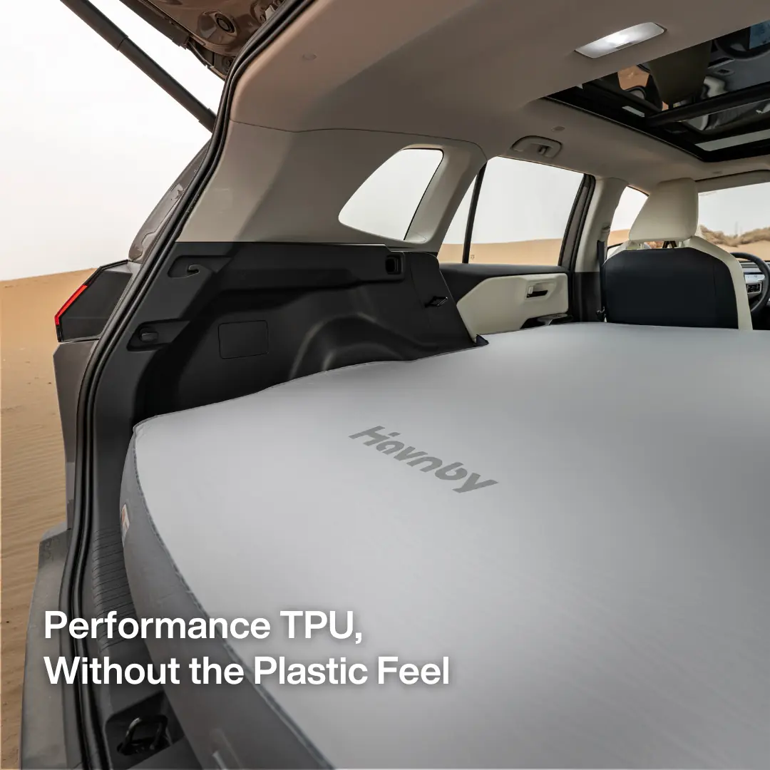 Havnby FlatCore Hybrid Support Mattress for Toyota RAV4 filling the vehicle's open rear cargo area, with the Havnby wordmark visible on the mattress surface and desert terrain visible through the open tailgate