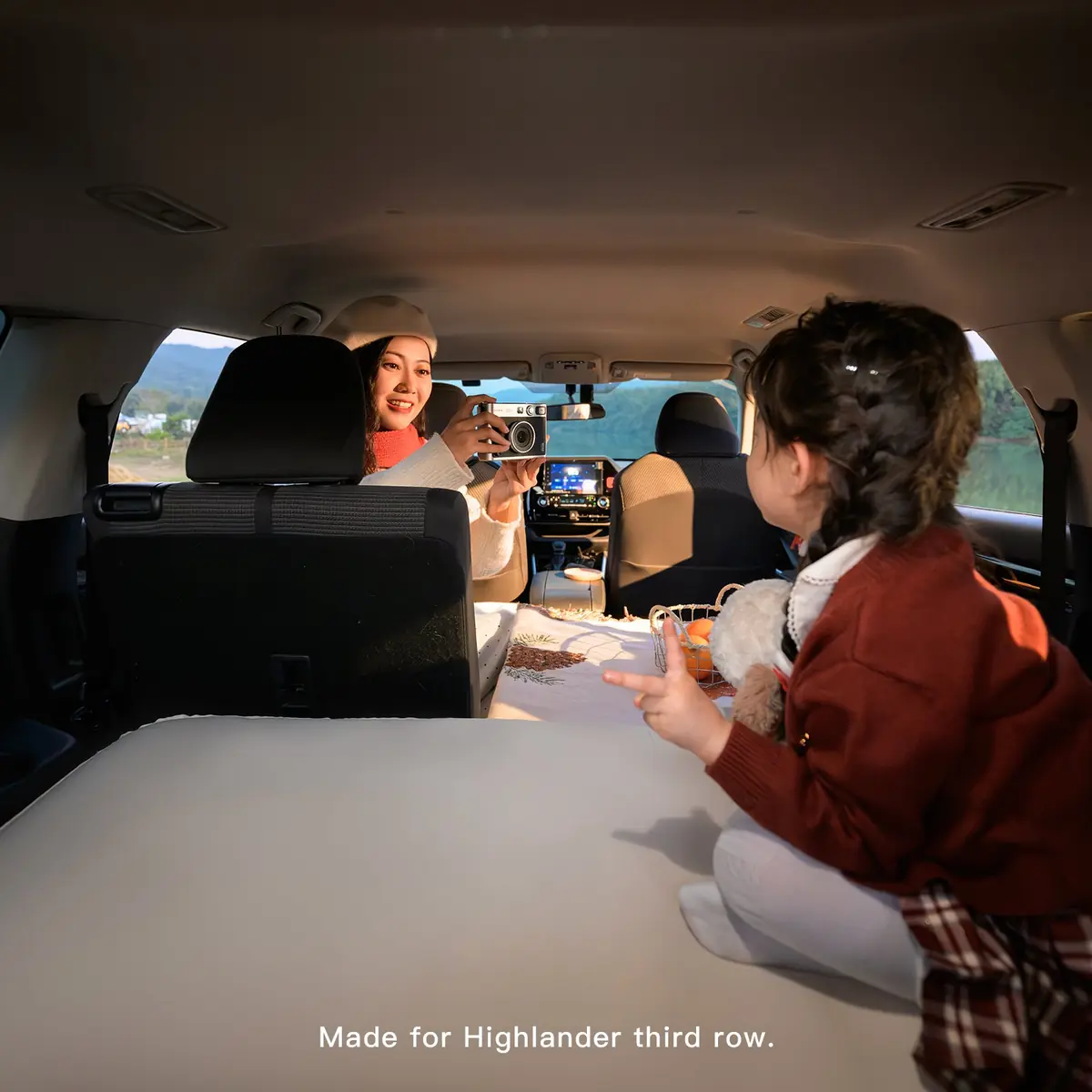Adult and child in a Toyota Highlander cabin with the Havnby MiniNest pad visible in the third row and on-image text reading Made for Highlander third row