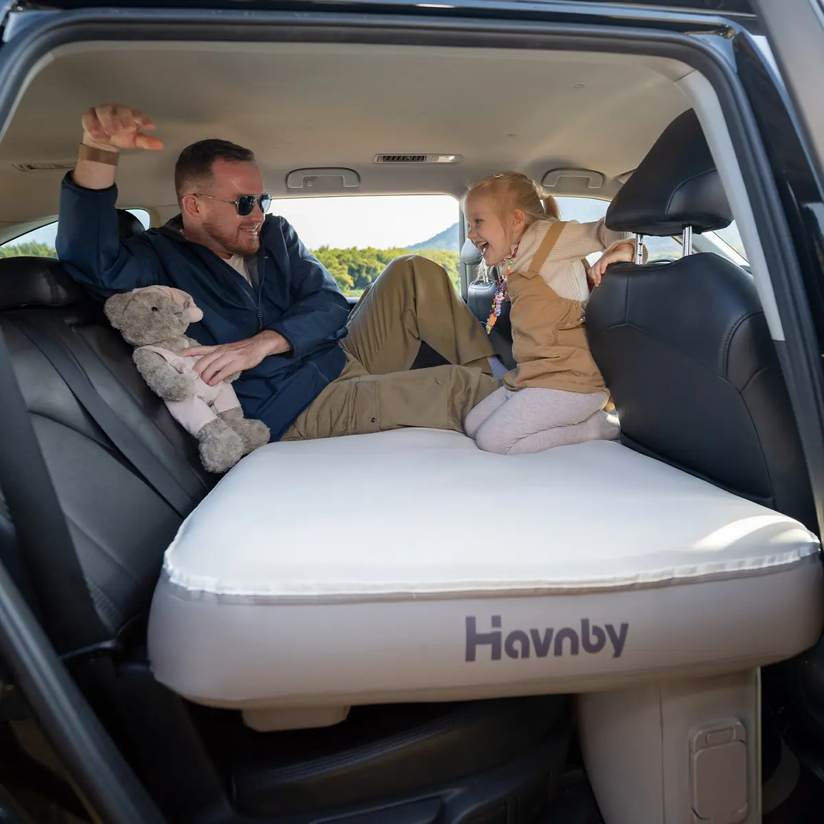 A man and a young girl playing on the Havnby SnugNest pad inside a Toyota Highlander with the rear hatch open