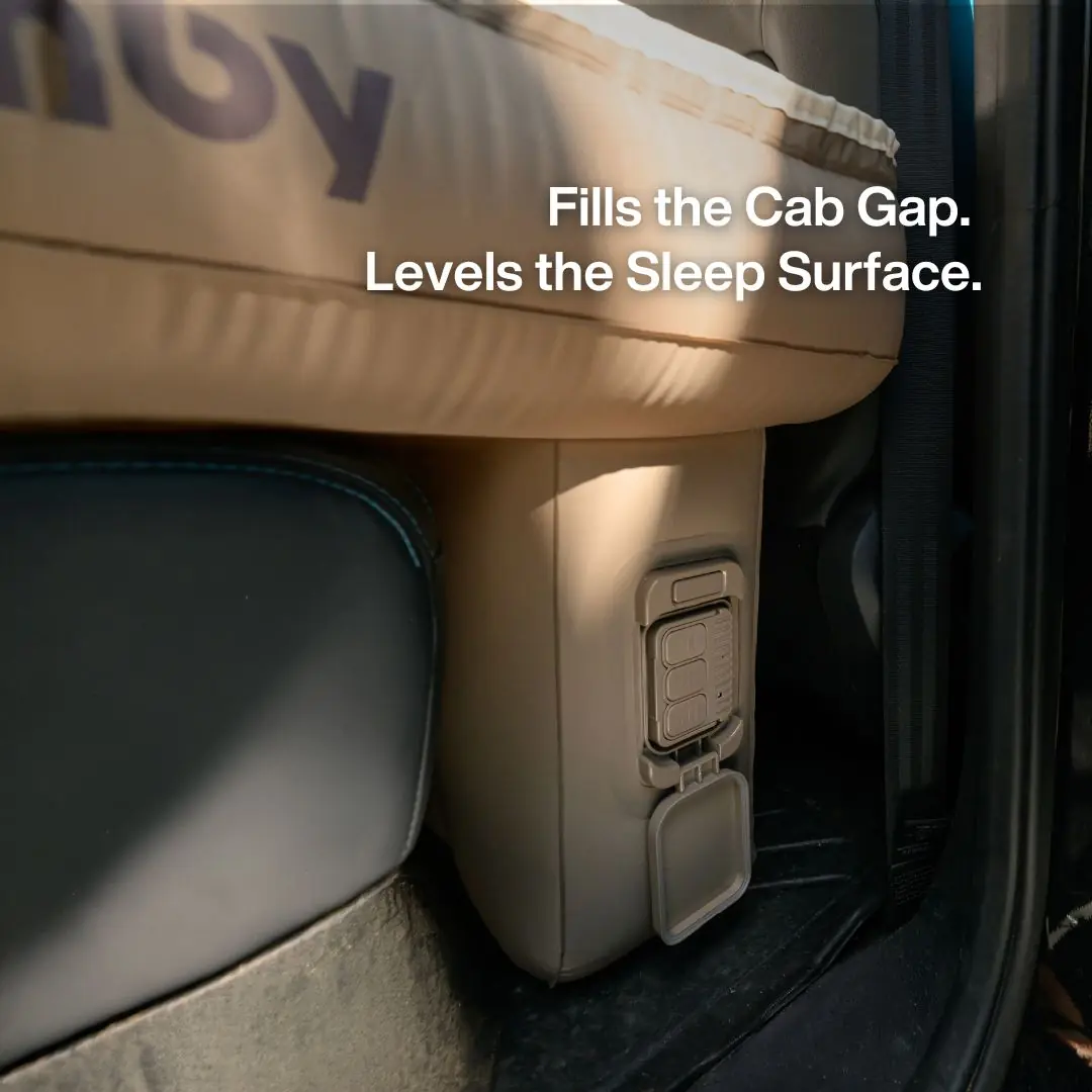Close-up of the Havnby SnugNest pump and valve module wedged into the truck cab footwell, with on-image text reading Fills the Cab Gap, Levels the Sleep Surface