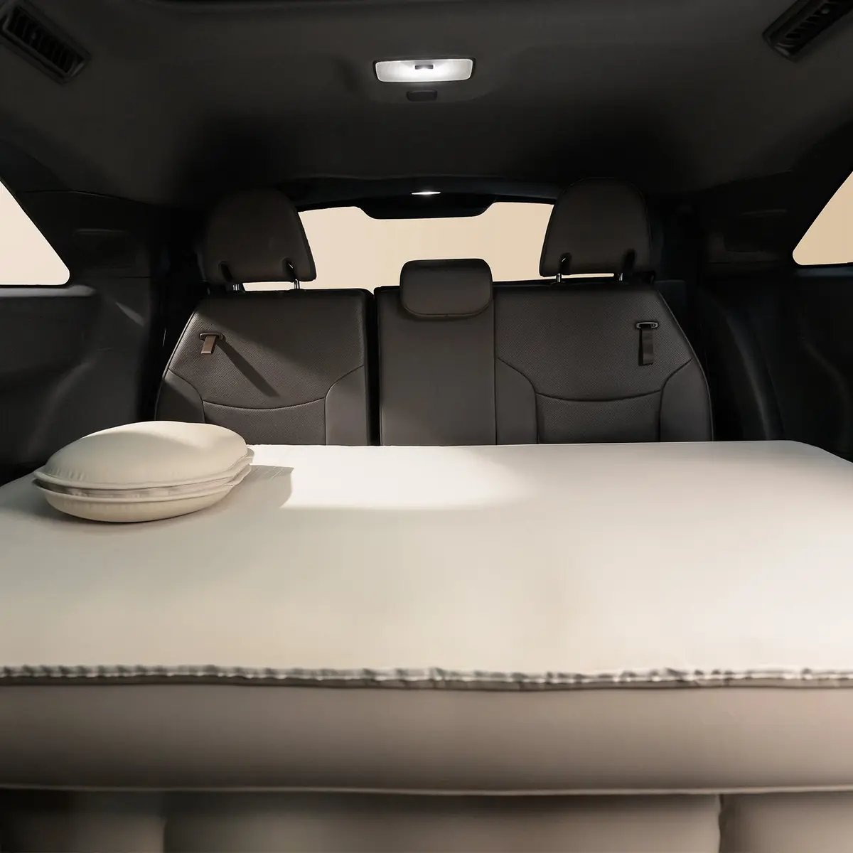 Havnby SnugNest pad installed across the third-row seat area of a minivan, with a pillow on top and the seat backs visible