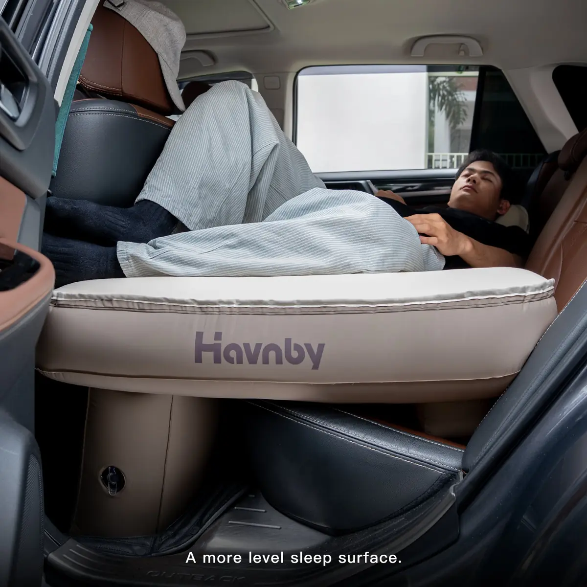 Man resting on the Havnby SnugNest Second-Row pad inside a Subaru Outback, with OUTBACK visible on the door sill plate