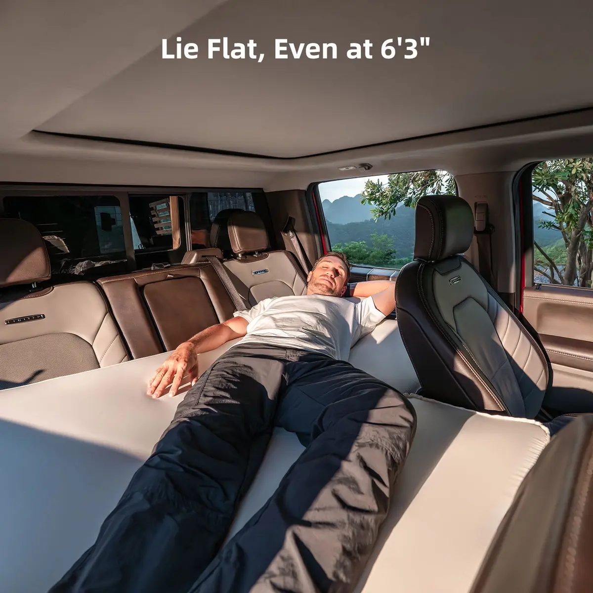 Man lying across the installed Havnby SnugNest Truck Sleep System pad and extension