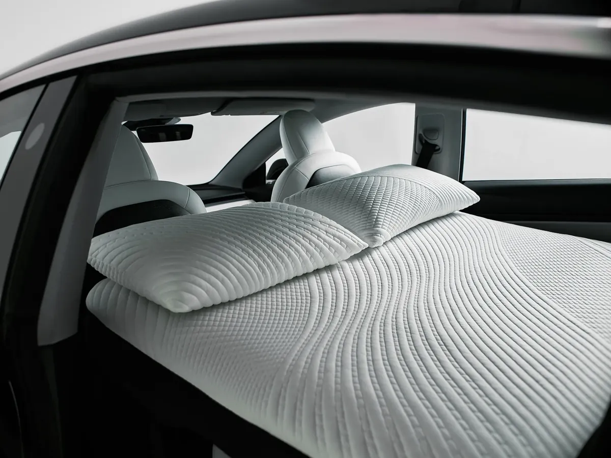 A Snuuzu bed with two pillows inside a Tesla Model 3 with the seats folded