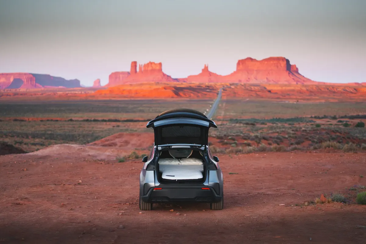 Tesla Model Y with the hatch open and a Snuuzu mattress inside, in Monument Valley