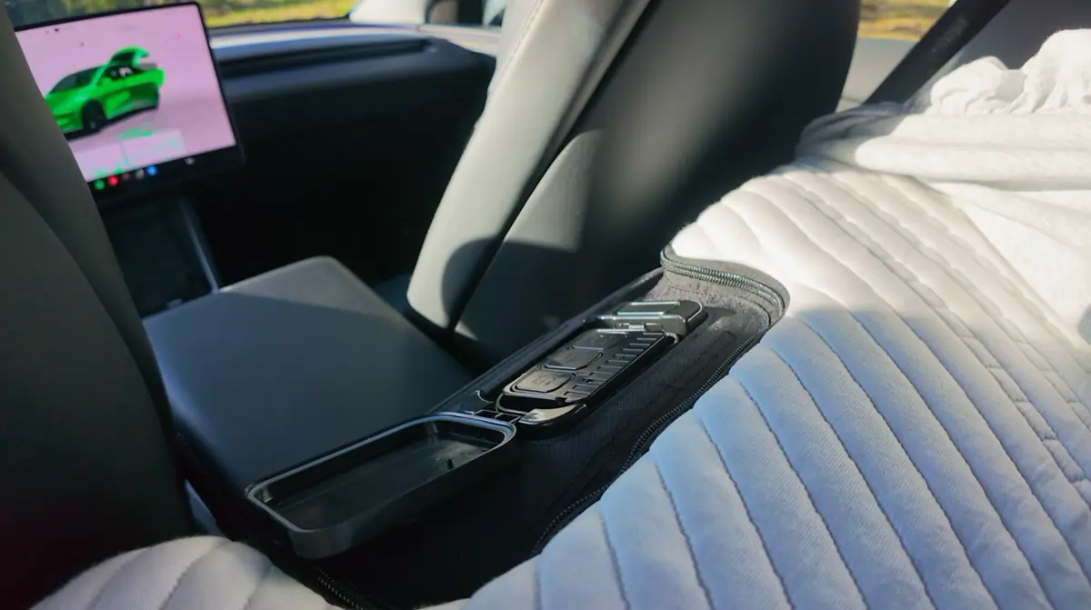 The removable Snuuzu pump docked in its pocket in the mattress, between the front seats of a Tesla Model Y