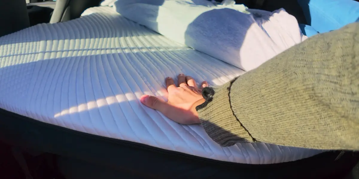 A hand pressing the quilted top cover of the operator’s Snuuzu Model Y