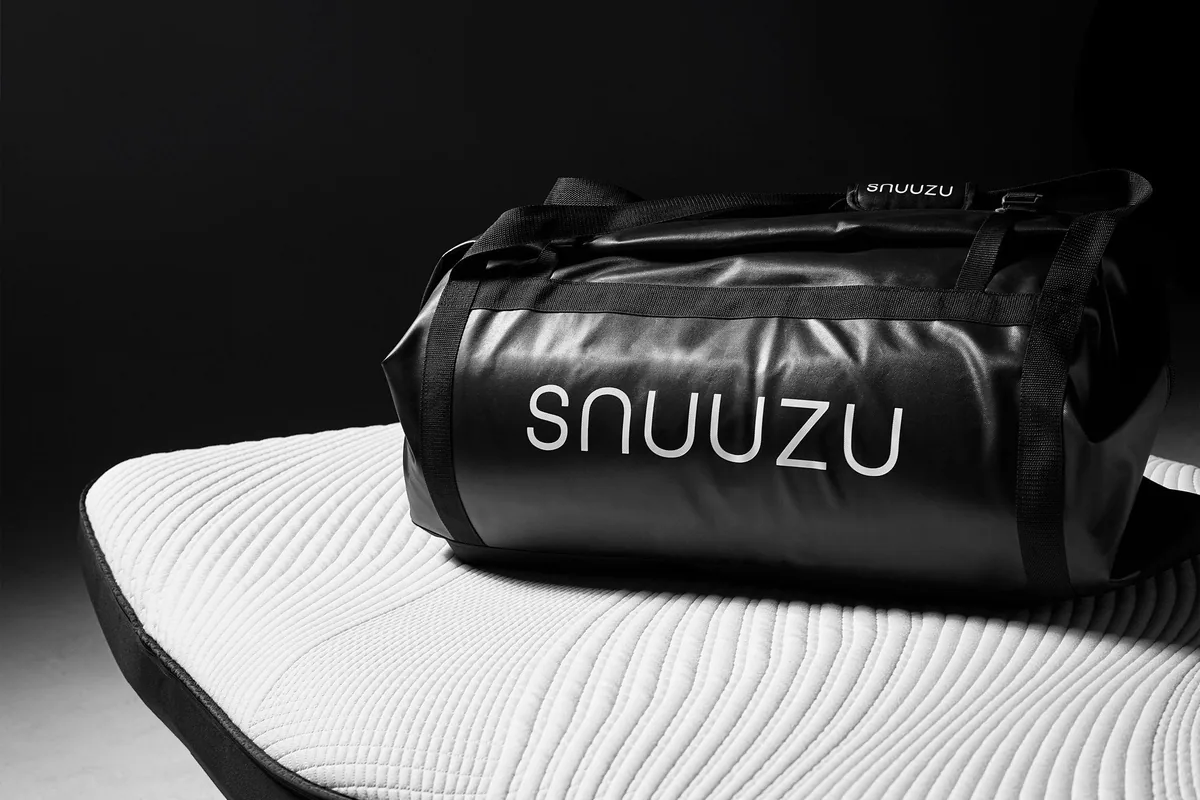 Snuuzu mattress beside its integrated black storage bag