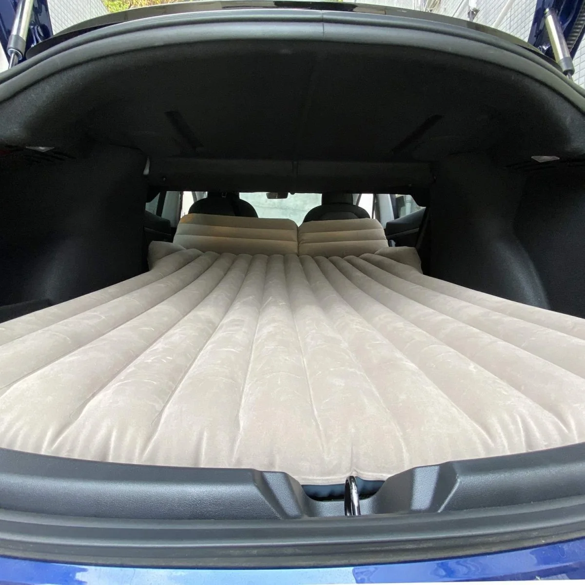 Beige T-Launch air mattress installed behind folded seats in a Tesla